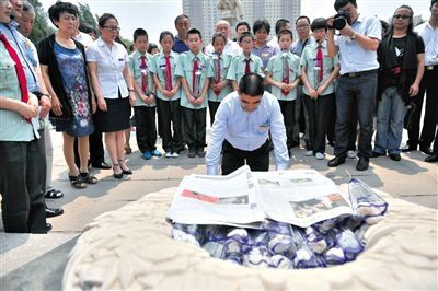 7月1日，辽宁省抚顺市，陈光标在雷锋墓前献上自己在美国接受报道的报纸，并下跪，连磕三个头。图/CFP